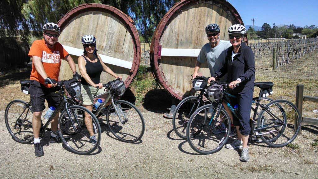 cyclists posing in front of wine casks